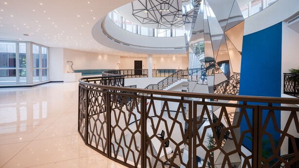 A modern interior with a central staircase, glass railings, and a polished floor. - Orion City Hotel (Colombo)