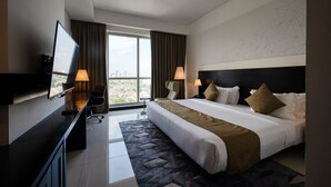 A modern hotel room with a large bed, two bedside lamps, a flat-screen TV, a desk with a chair, and a city view. - Orion City Hotel (Colombo)