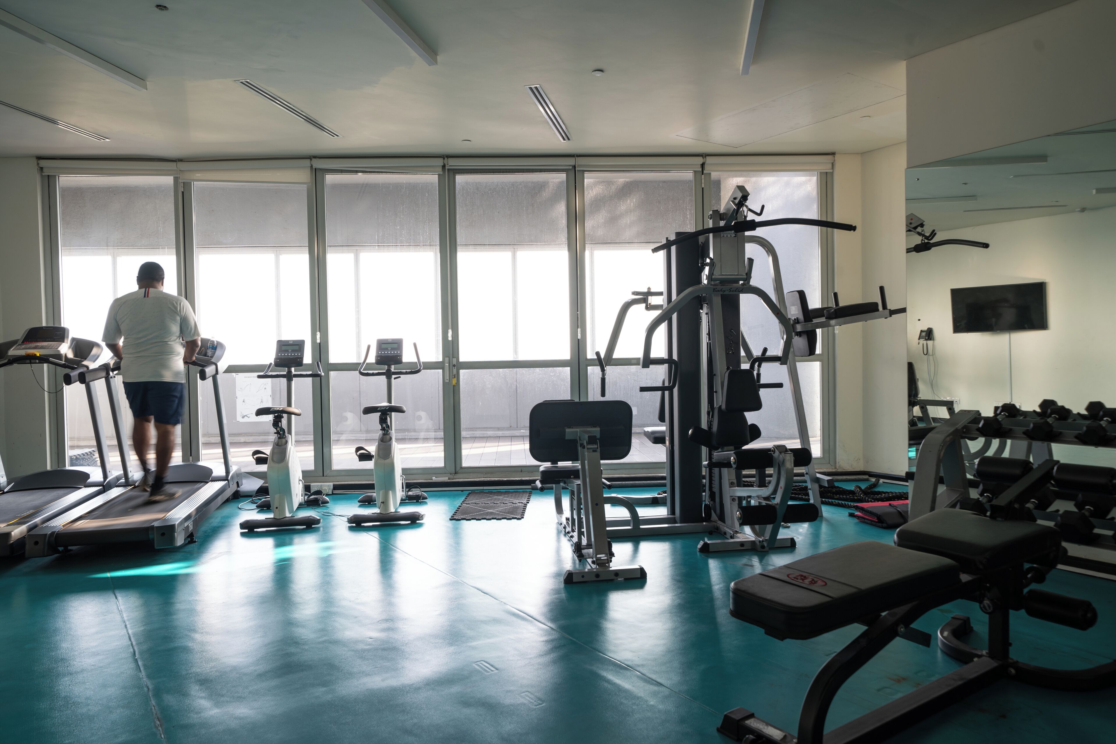 A gym with treadmills, weight machines, and a large window.