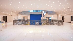 A spacious lobby with a high ceiling, a central blue structure, and a modern design. - Orion City Hotel (Colombo)
