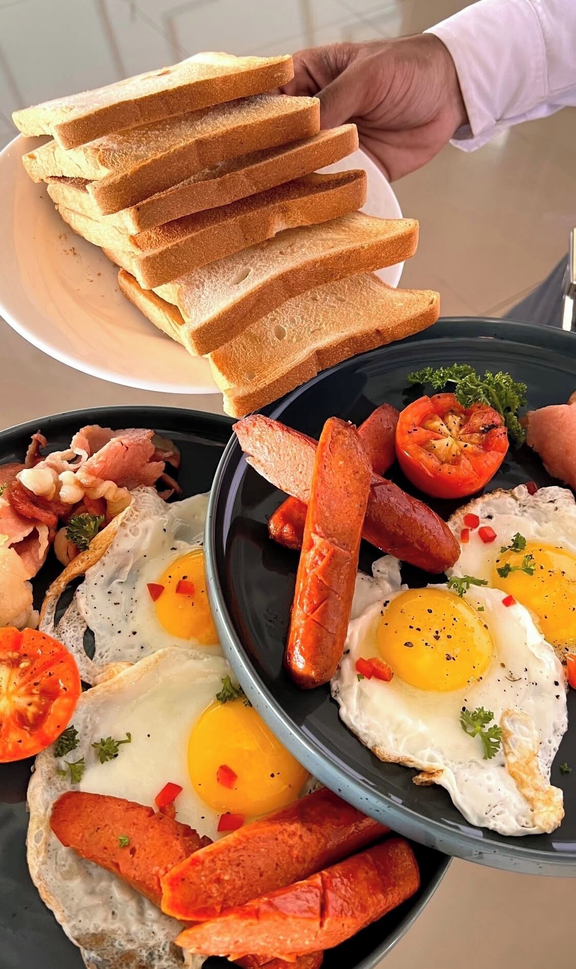 A plate of food with toast, sausages, eggs, and tomatoes.