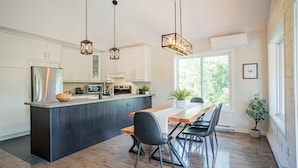 Una cocina moderna con una isla central, mesa de comedor de madera y sillas negras.