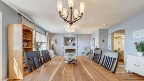 A dining room with a long wooden table, black chairs, a chandelier, and a white cabinet. - Whistler Hollow! Family Home, Bball Court, Firepit (Colorado Springs)