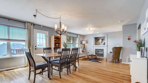 A spacious living room with a dining area, a fireplace, and a large window with blinds. - Whistler Hollow! Family Home, Bball Court, Firepit (Colorado Springs)