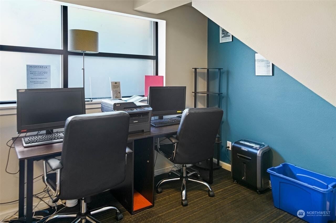 Un espace de travail comprenant deux bureaux, des ordinateurs et des chaises de bureau.