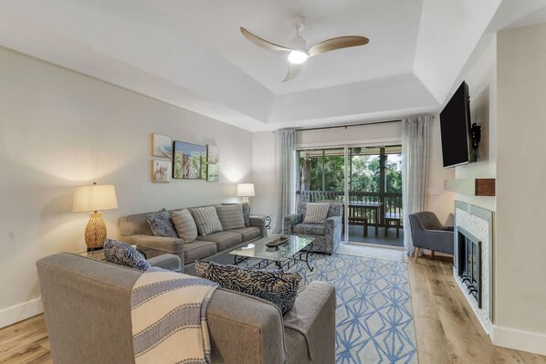 A living room with a sofa set, a coffee table, a TV mounted on the wall, and a fireplace.