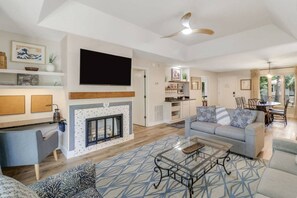 A modern living room with a fireplace, a flat-screen TV, and a dining area with outdoor access.
