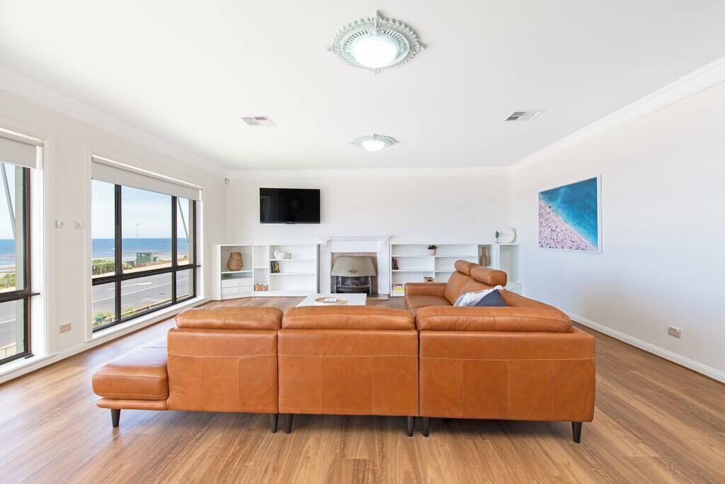 A spacious living room with a large window, a fireplace, and a modern sofa.