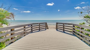 En träpromenad som leder till en strand med en klar himmel.