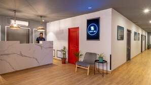 Un espace d’accueil moderne avec un comptoir de réception en marbre, une porte rouge et une enseigne indiquant « LOFT 24 ».