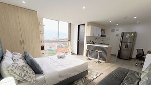 Eine moderne Wohnung mit Bett, einer Couch, einer Küchenzeile und Blick auf die Stadt.