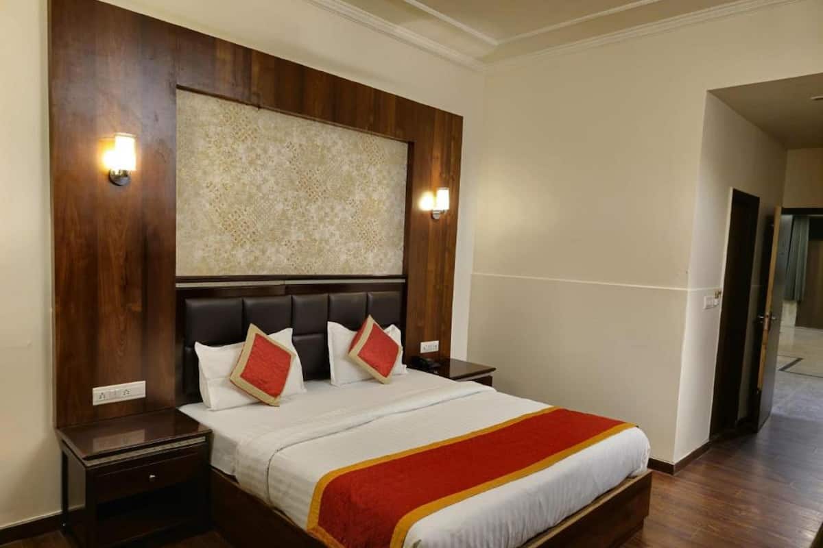 Ein Hotelzimmer mit einem großen Bett, einem Holz-Kopfteil, zwei Nachttischen und einer Wandleuchte.