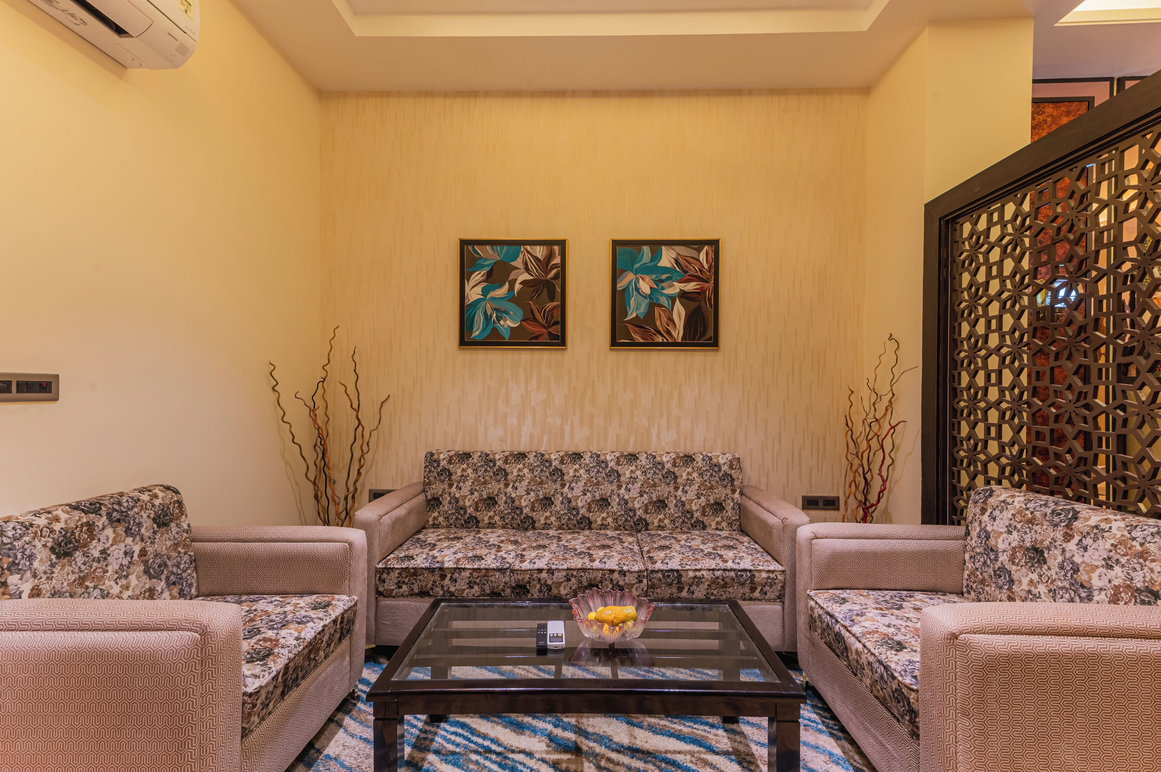 A living room with a sofa set, a coffee table with a bowl, and two wall-mounted paintings.