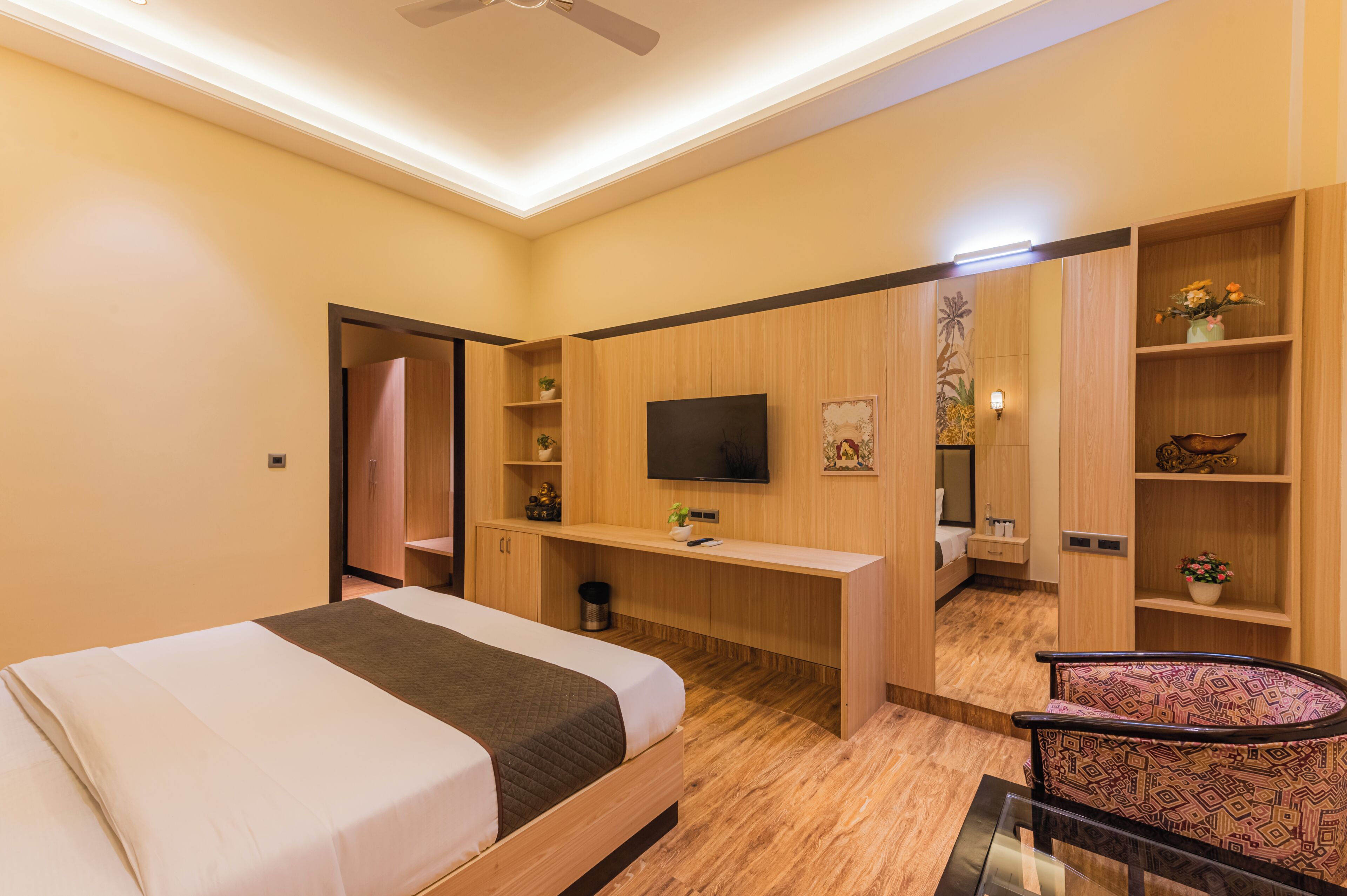 A modern hotel room with a bed, a desk, a TV, and a chair.
