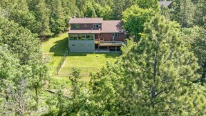 A two-story house with a large front yard, surrounded by dense forest. - Secluded & Spacious Cabin W/ a Spa and Garage (Sturgis)