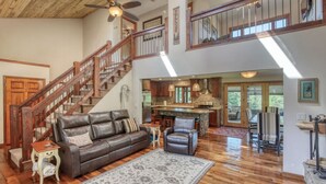 A spacious living area with a leather sofa, a dining table, and a kitchen in the background. - Secluded & Spacious Cabin W/ a Spa and Garage (Sturgis)