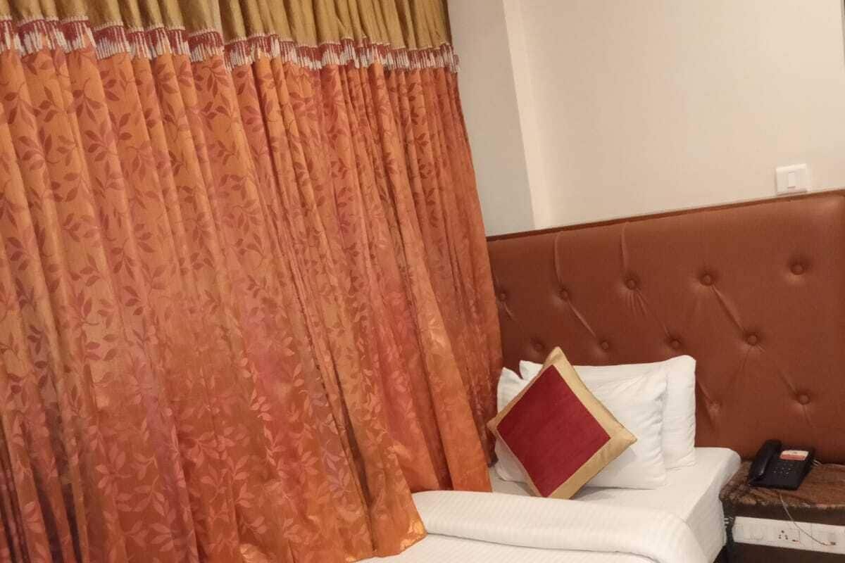 Ein Hotelzimmer mit Bett, Nachttisch mit Telefon und einem Fenster mit Vorhängen.
