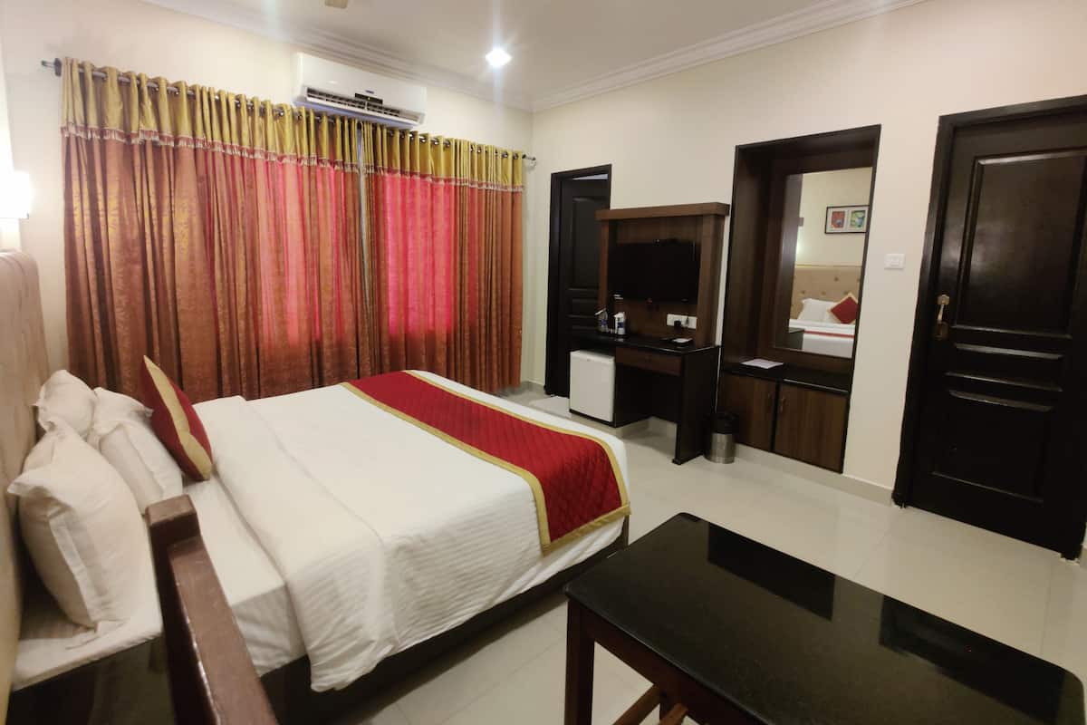Ein Hotelzimmer mit Bett, Schreibtisch, Spiegel, Kleiderschrank und Deckenventilator.