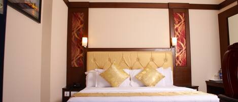 A hotel room with a large bed, wooden headboard, and two bedside tables.