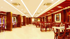 A spacious hotel lobby with multiple dining areas, wooden paneling, and modern lighting. - Hotel Sahana Castle (Nagercoil)
