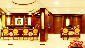 A hotel lobby with a reception desk, seating area with sofas, and a dining area with tables and chairs. - Hotel Sahana Castle (Nagercoil)