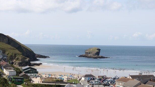 A coastal town with a beach, a rocky outcrop, and buildings along the shore. - Apple Tree Bungalow (Redruth)