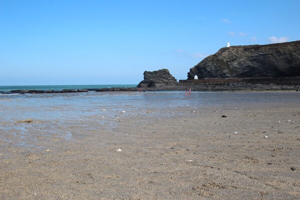 A beach with a rocky cliff and a lighthouse.