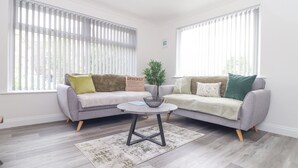 A modern living room with two grey sofas, a round coffee table, and a potted plant. - Apple Tree Bungalow (Redruth)