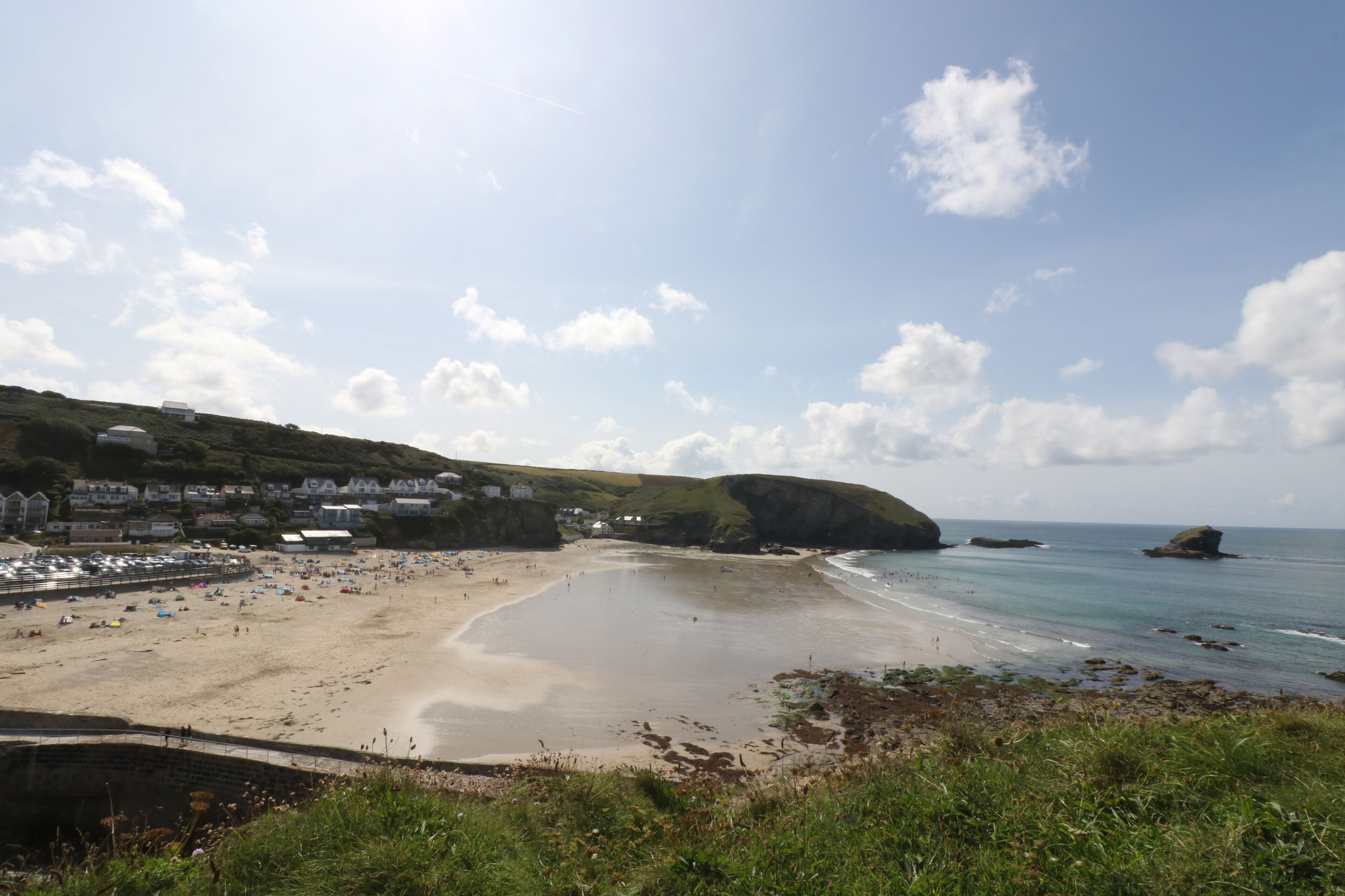 A beach with a sandy shore, a few buildings in the background, and a clear sky.