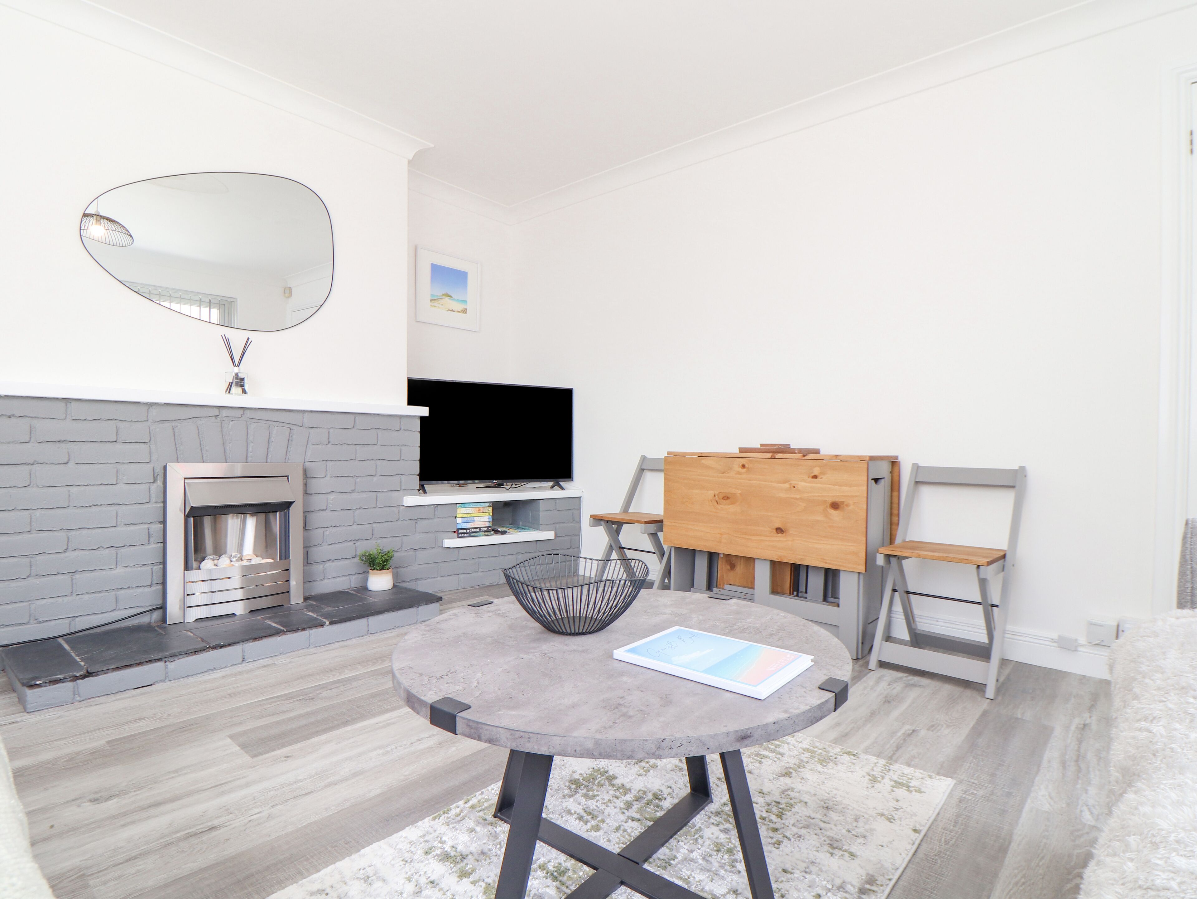 A modern living room with a fireplace, a round table, and a television.