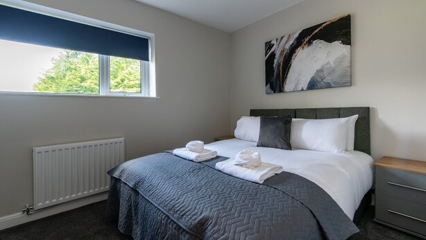 A bedroom with a bed, a radiator, a window, and a painting on the wall.