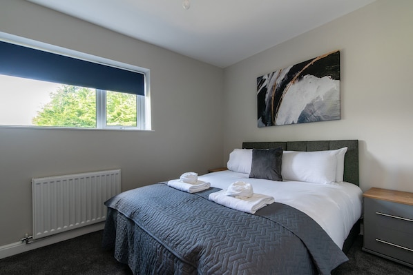 A bedroom with a bed, a radiator, a window, and a painting on the wall.
