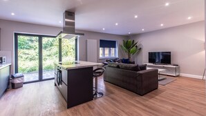 A modern kitchen with a central island, a dining area with a sofa, and a TV on a stand.