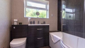 A modern bathroom with a toilet, vanity, and bathtub.