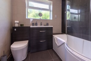 A modern bathroom with a toilet, vanity, and bathtub.