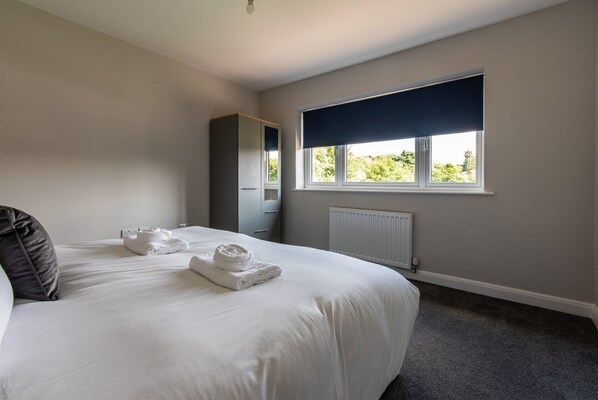 Un dormitorio con una cama grande, ventana con vistas, un radiador y un armario.