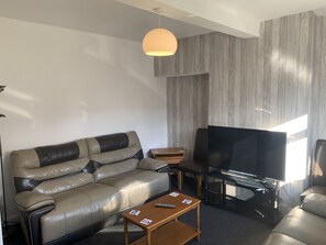Relax in this stylish living room with a leather sofa, flat-screen TV, and pendant light.