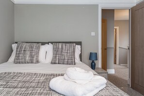 A hotel room with a bed, pillows, a bedside lamp, and a towel on the bed.