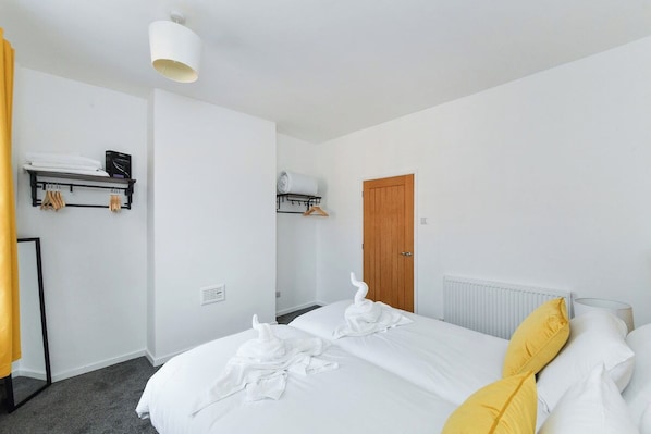 A hotel room with a bed, a wardrobe, a radiator, and a shelf with towels.