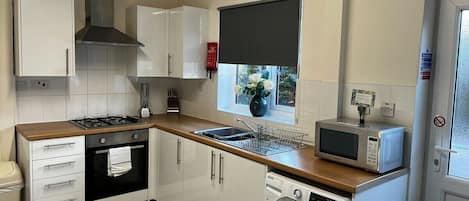 A compact kitchen with a stove, oven, microwave, and washing machine.