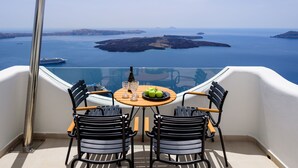 A balcony with a table set for two, overlooking a scenic view of the sea and islands. - Aethria Suite with Caldera view (Santorini)