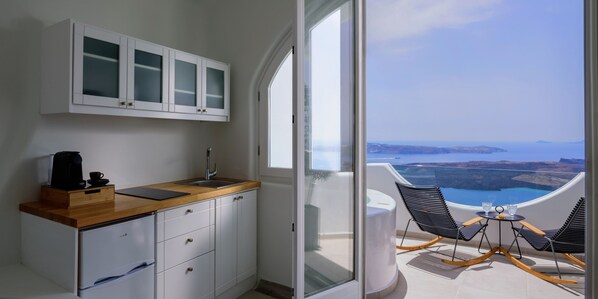 A modern kitchen with a wooden countertop, white cabinets, and a view of a scenic landscape through a large window.