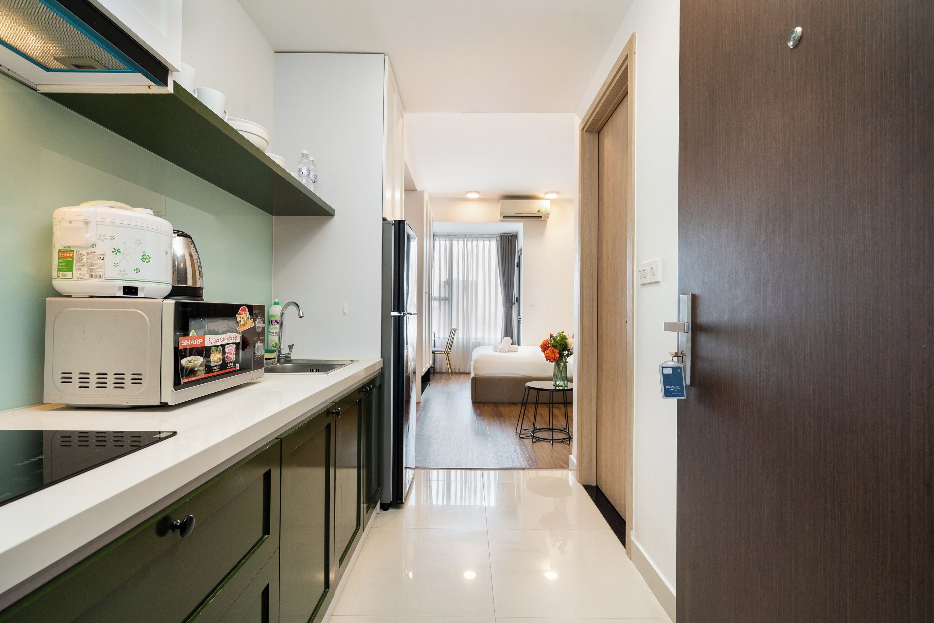 Una cocina moderna equipada con microondas, cocedor de arroz y cafetera. Hay una zona de comedor con mesa y sillas.