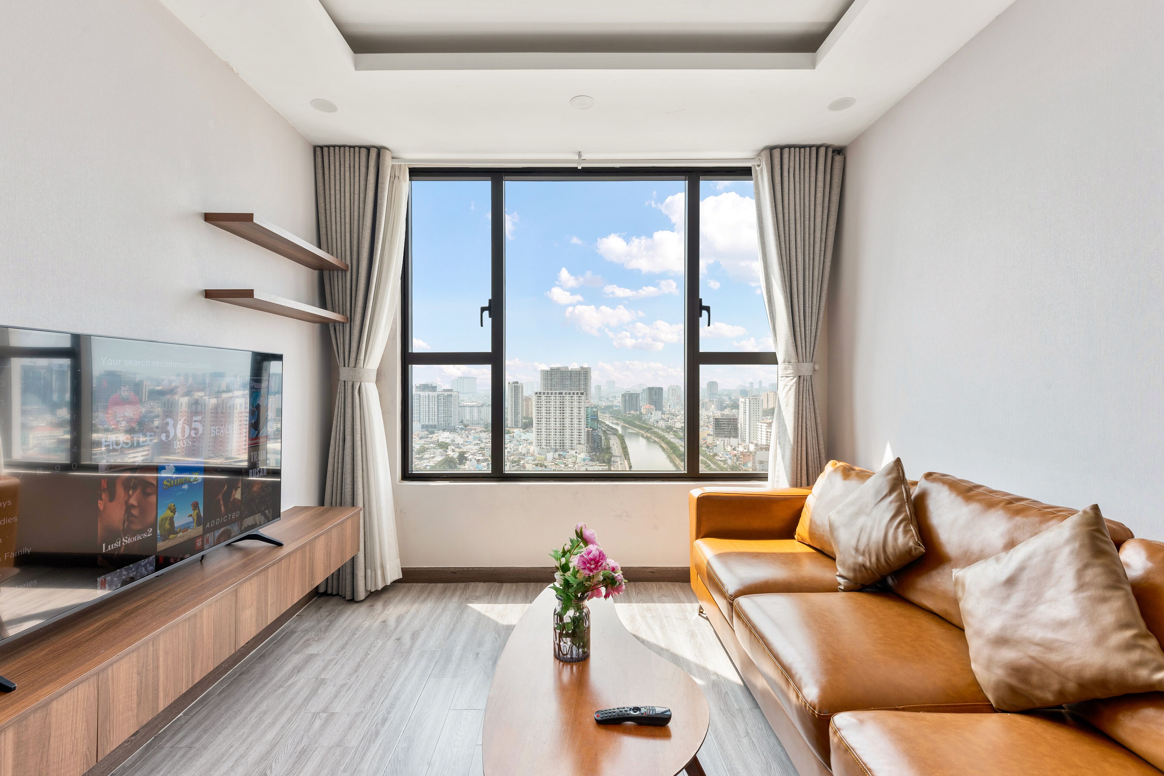 Ein modernes Wohnzimmer mit großem Fenster, Flachbildfernseher, Sofa und Couchtisch.