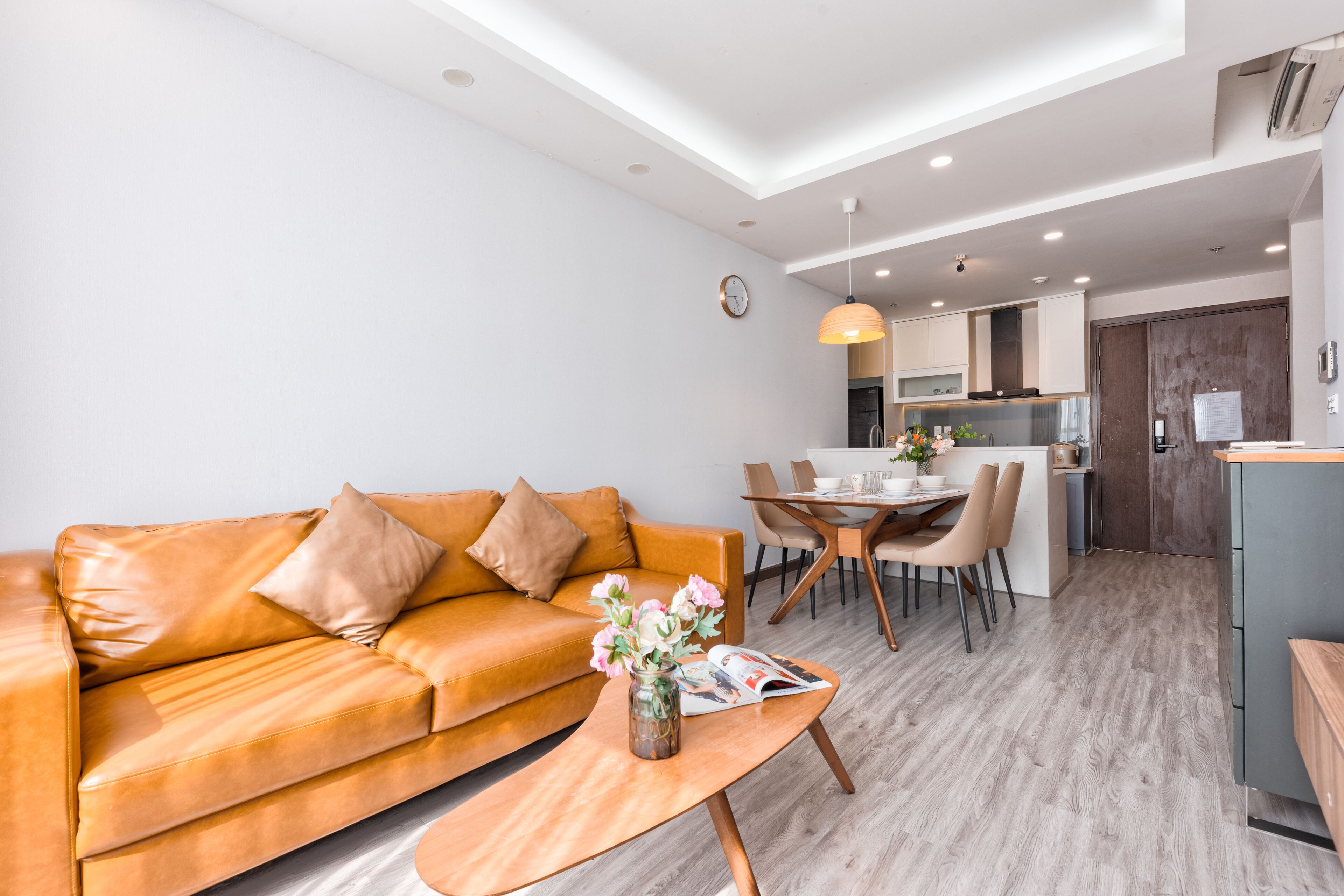 A modern living room with a leather sofa, a wooden coffee table, and a dining area with a table and chairs.