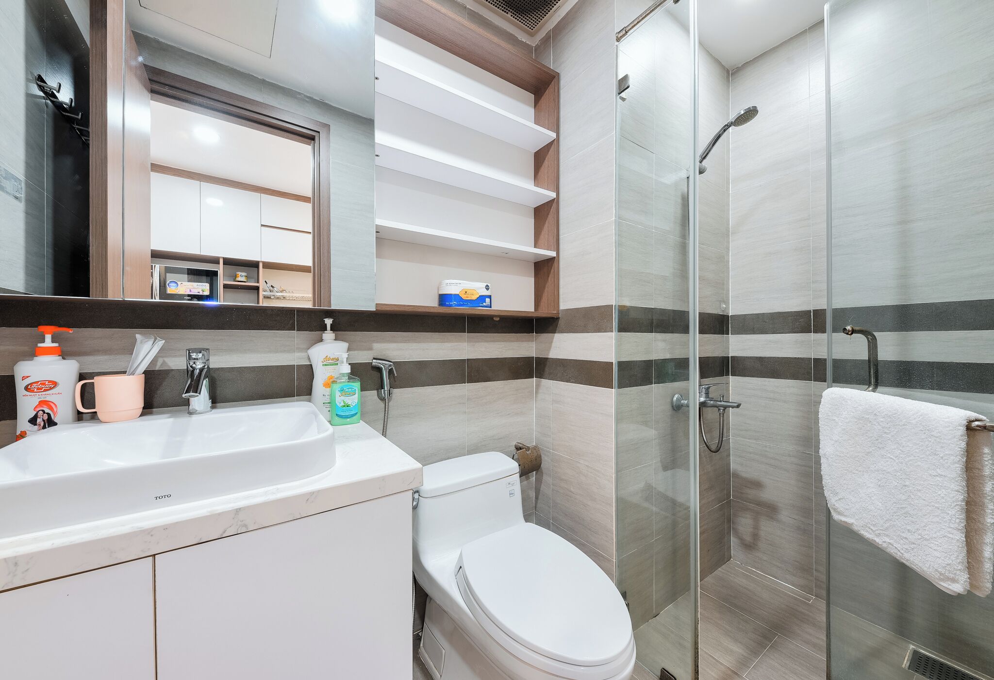 A modern bathroom with a white sink, toilet, and glass-enclosed shower.