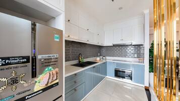 A modern kitchen with white cabinets, a grey backsplash, and a stainless steel sink.