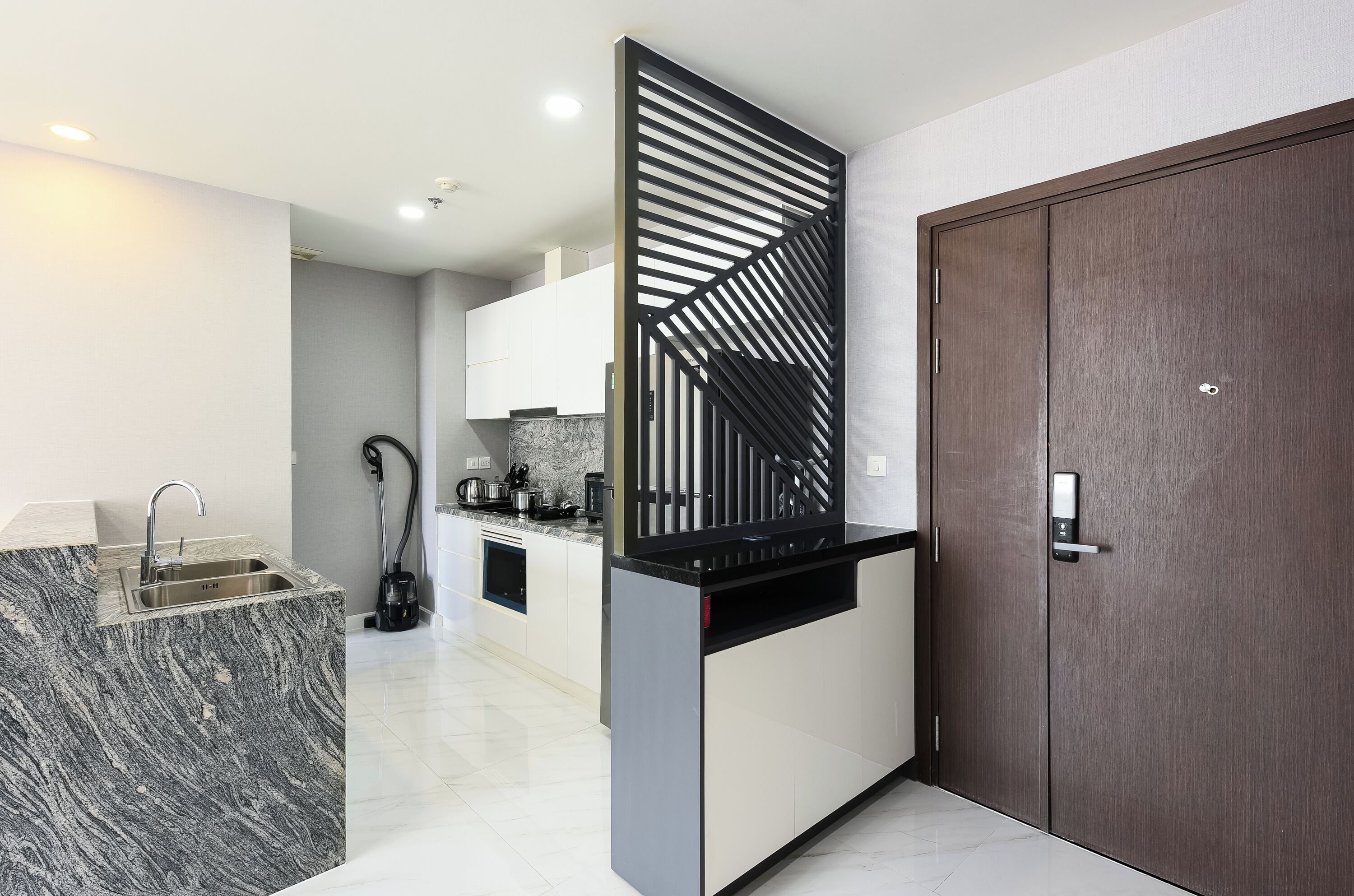 A modern kitchen with a marble countertop, a built-in sink, and a black decorative panel.