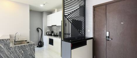 A modern kitchen with a marble countertop, a built-in sink, and a black decorative panel.