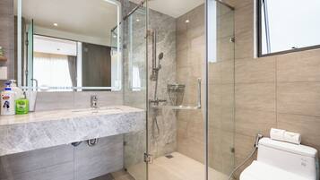 A modern bathroom with a glass-enclosed shower, a marble sink, and a toilet.